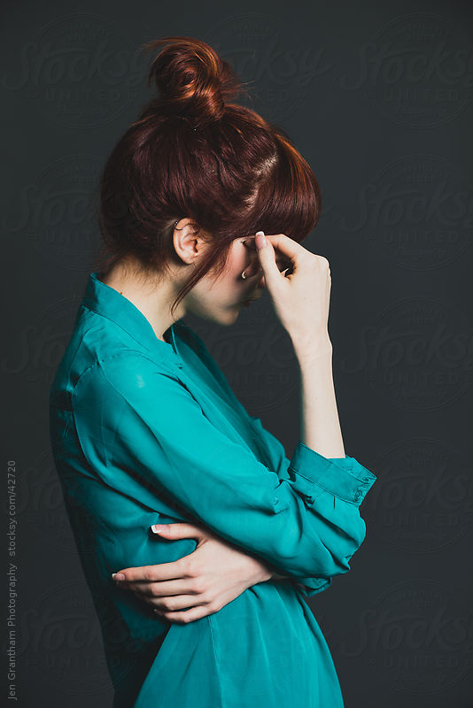 Side view of redheaded young woman covering her face