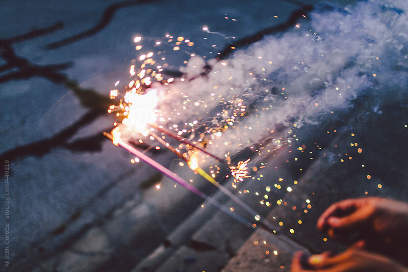 Handfull of sparklers going off at night by Kristen Curette