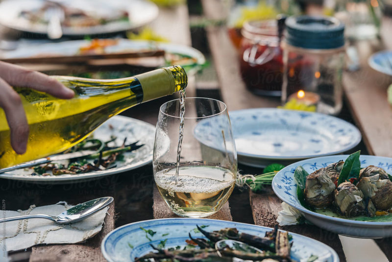 Stock photo of someone pouring wine at a dinner party