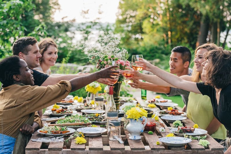 Friends toasting with wine at outdoor summer feast